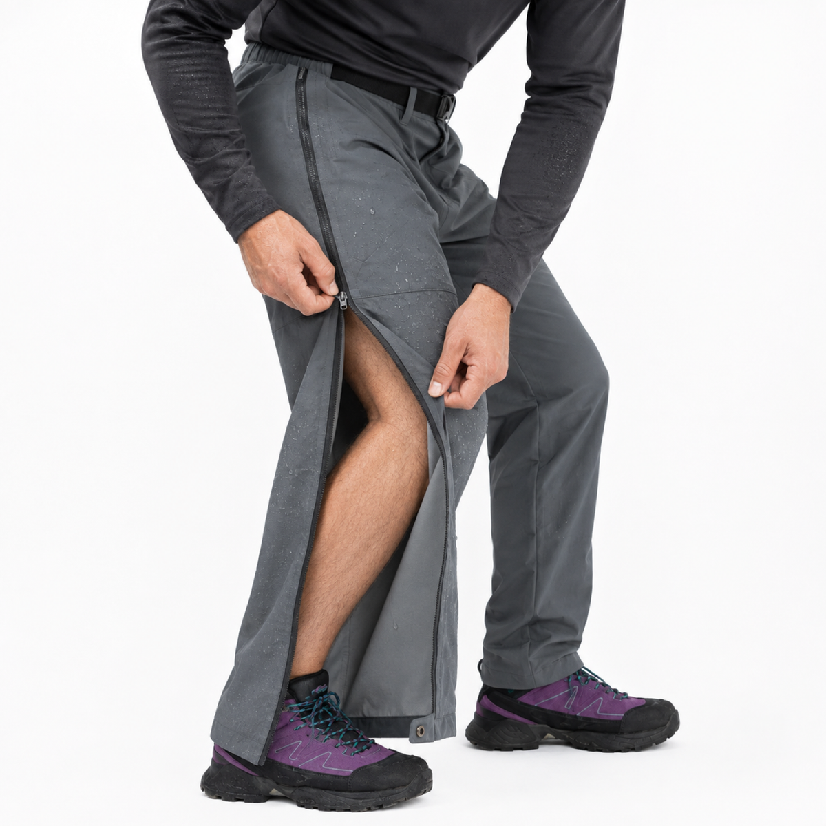 Grey Wye walking trousers with the full-length side zip half open, shown on a slightly crouching model with a bare leg and rain droplets on the outer fabric.